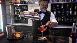 A bartender pouring a drink into a martini glass. - Hotel Meridian Inn (Palayankottai)