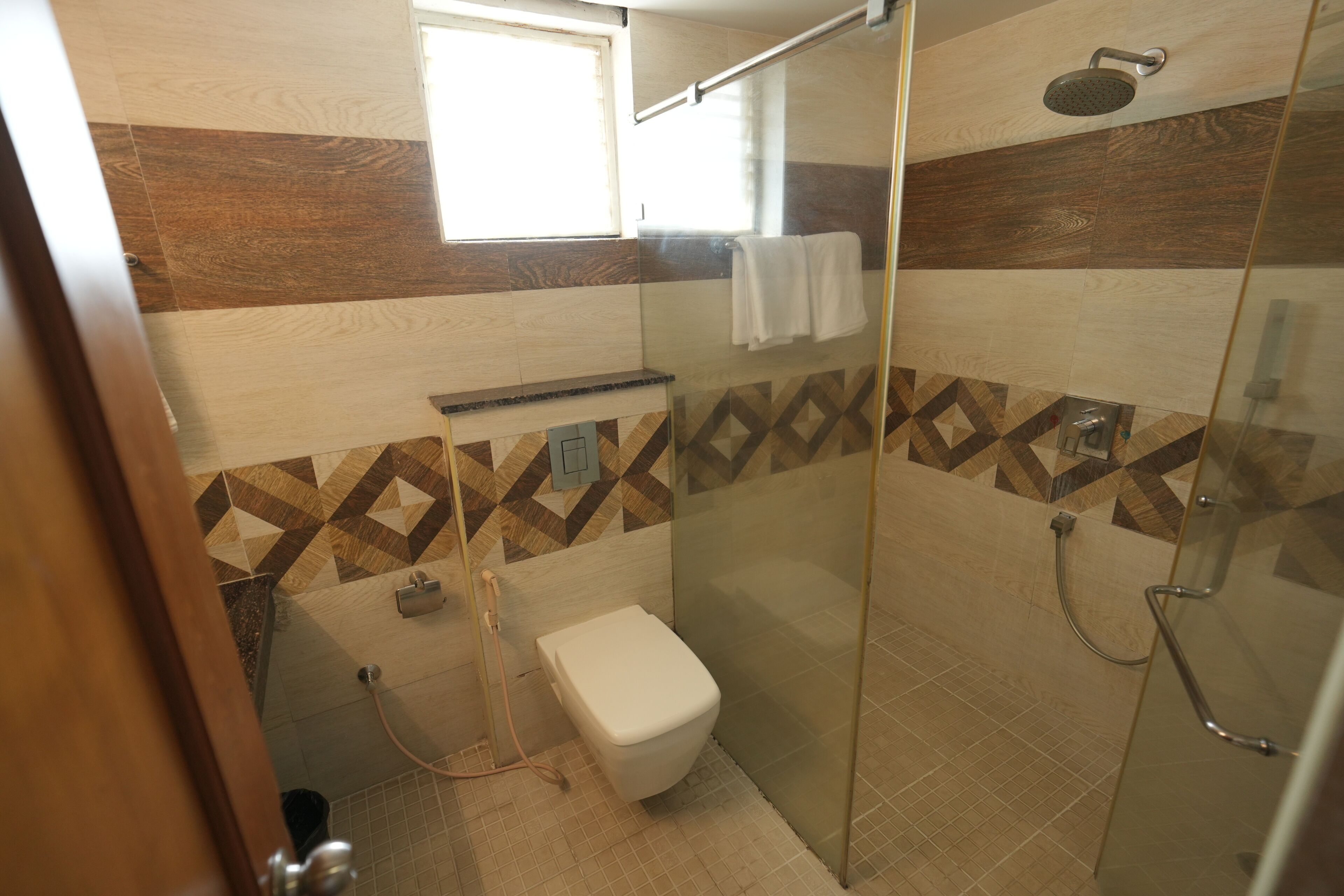 Une salle de bain moderne avec une douche à parois de verre, des toilettes et un porte-serviettes.