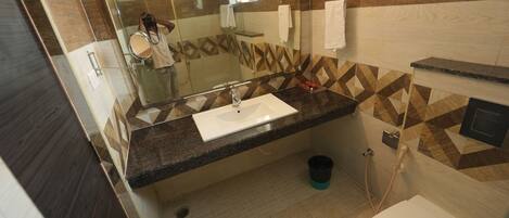 A bathroom with a glass shower enclosure, a sink with a mirror, and a toilet.