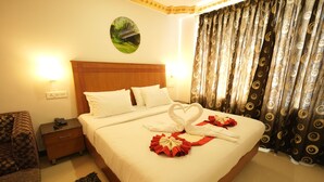 A hotel room with a neatly made bed, a nightstand with a phone, and a wall-mounted picture. - Hotel Meridian Inn (Palayankottai)