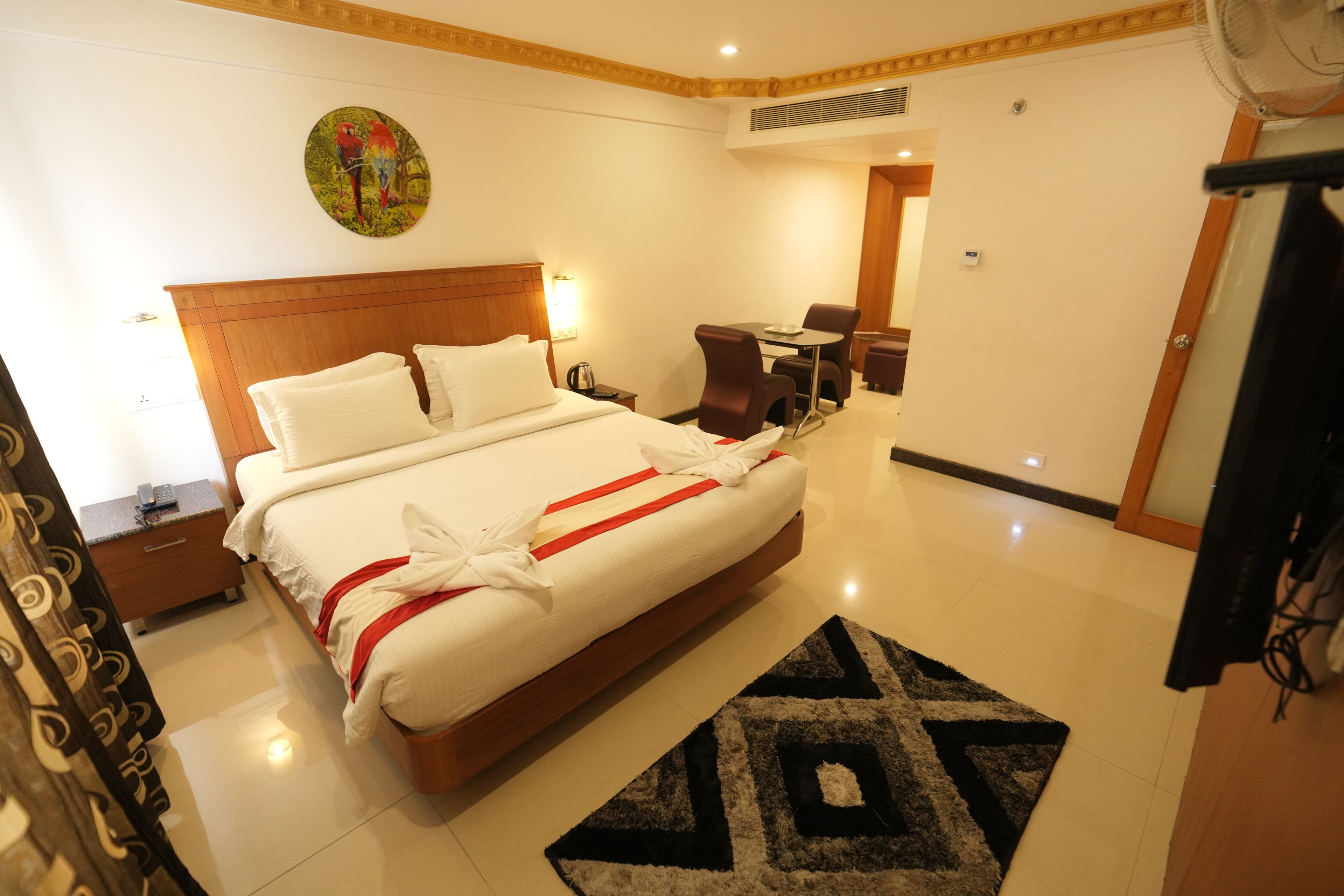 A hotel room with a large bed, a desk, a chair, and a small table.