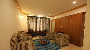 A living room with patterned sofas, a coffee table, and curtains. - Hotel Meridian Inn (Palayankottai)