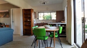 A dining area with a round table and green chairs, a kitchen with a window, and a blue sofa. - Studio - C ~ Perfect for your holidays (Cunjurong Point)
