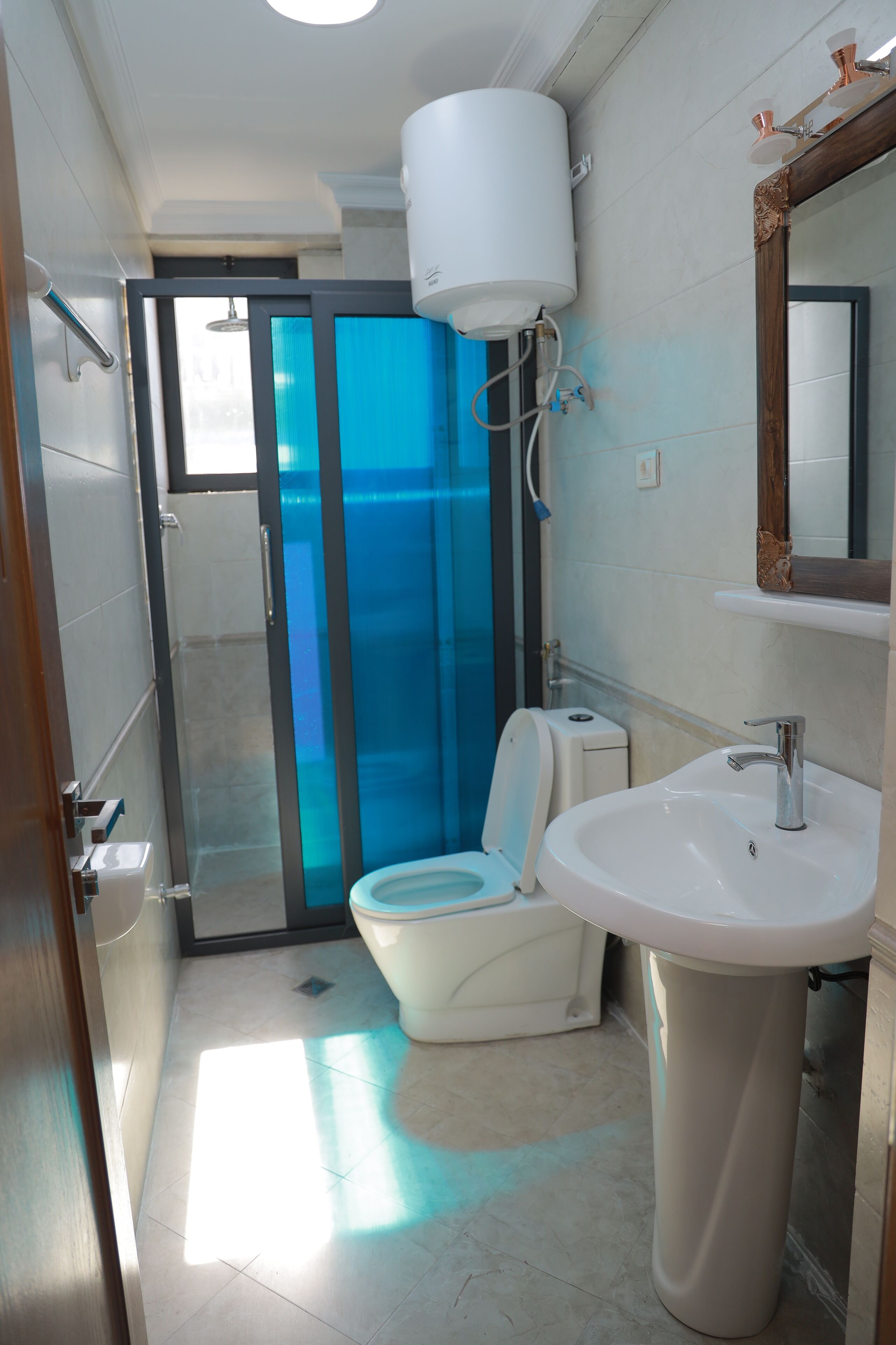 A modern bathroom with a toilet, sink, and glass shower enclosure.