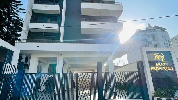 A multi-story building with a gated entrance, a clear sky, and a visible sign for Abat Properties. - Abat property (Addis Ababa)