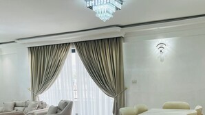 A spacious living room with a wooden floor, a dining area with a table and chairs, and a chandelier. - Abat property (Addis Ababa)