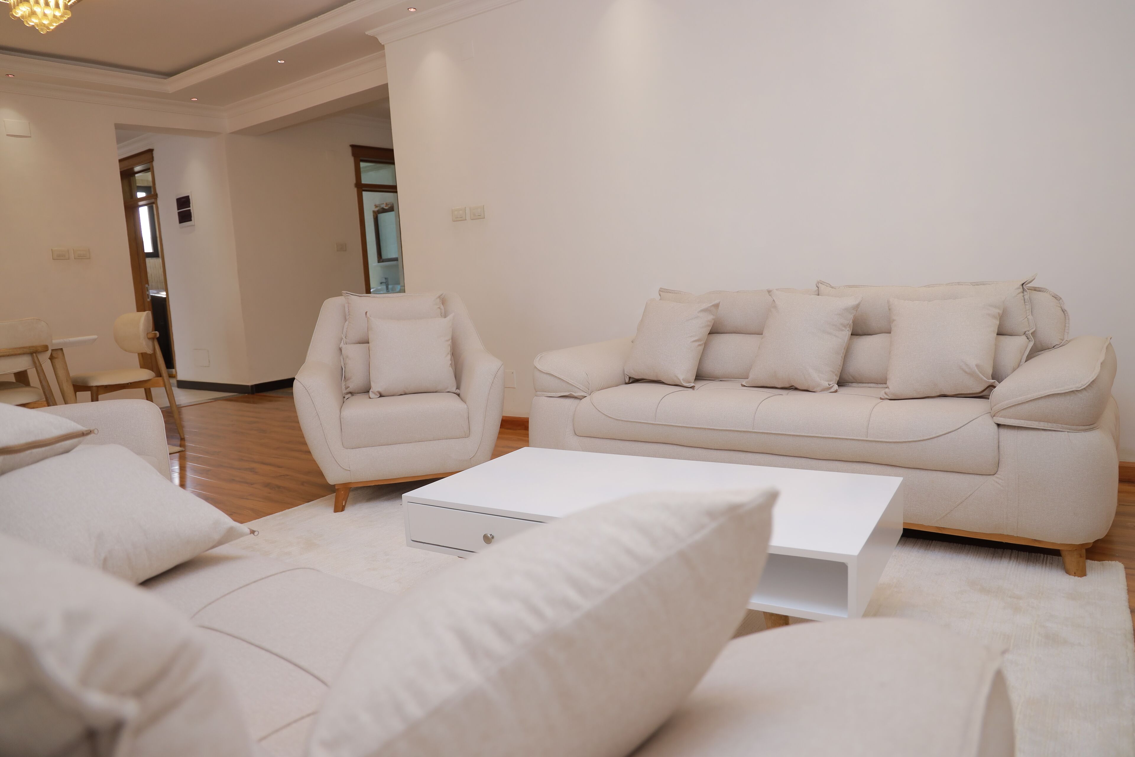 A modern living room with a beige sofa, armchairs, and a white coffee table.