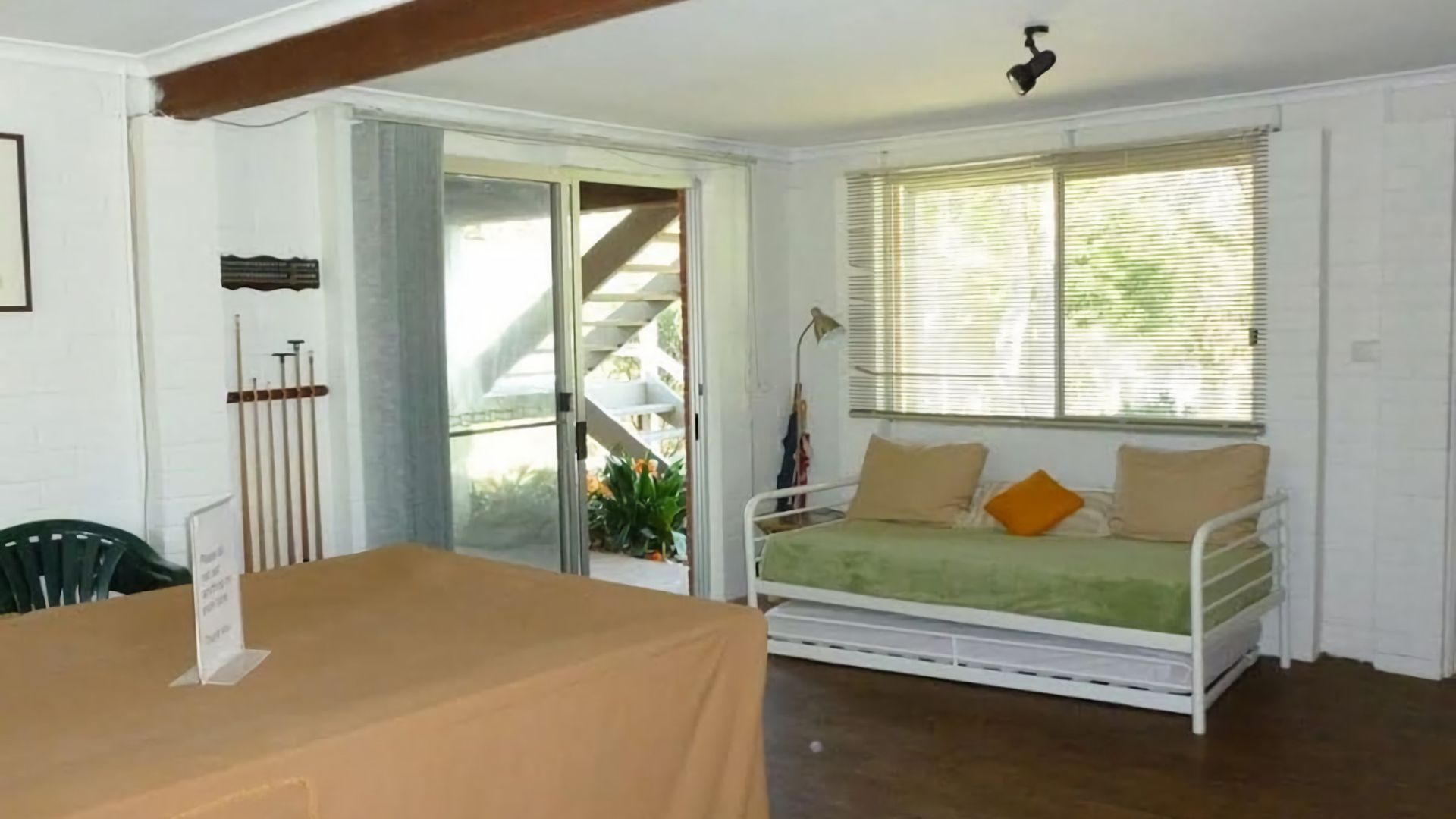 Ein Zimmer mit einem Bett, einem Tisch und einer Treppe, die zu einem Außenbereich führt.