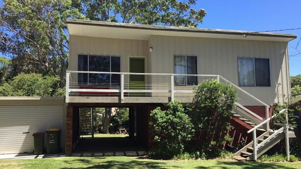 Uma casa de dois andares com varanda, um alpendre e escadas que levam ao andar superior.