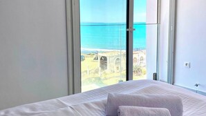 Une chambre d’hôtel avec un lit, deux serviettes, une vue sur la mer et un balcon.