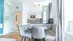 Eine moderne Küche mit einer zentralen Kochinsel, einem Essbereich mit gesteppten Stühlen und einem großen Spiegel über der Arbeitsfläche.