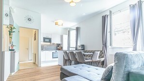 Eine moderne Wohnung mit Essbereich, Küche und Wohnzimmer mit Sofa und einem Vorhangfenster.