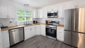 A modern kitchen with white cabinets, stainless steel appliances, and a wooden countertop. - Forks Riverside Serenity (Forks)