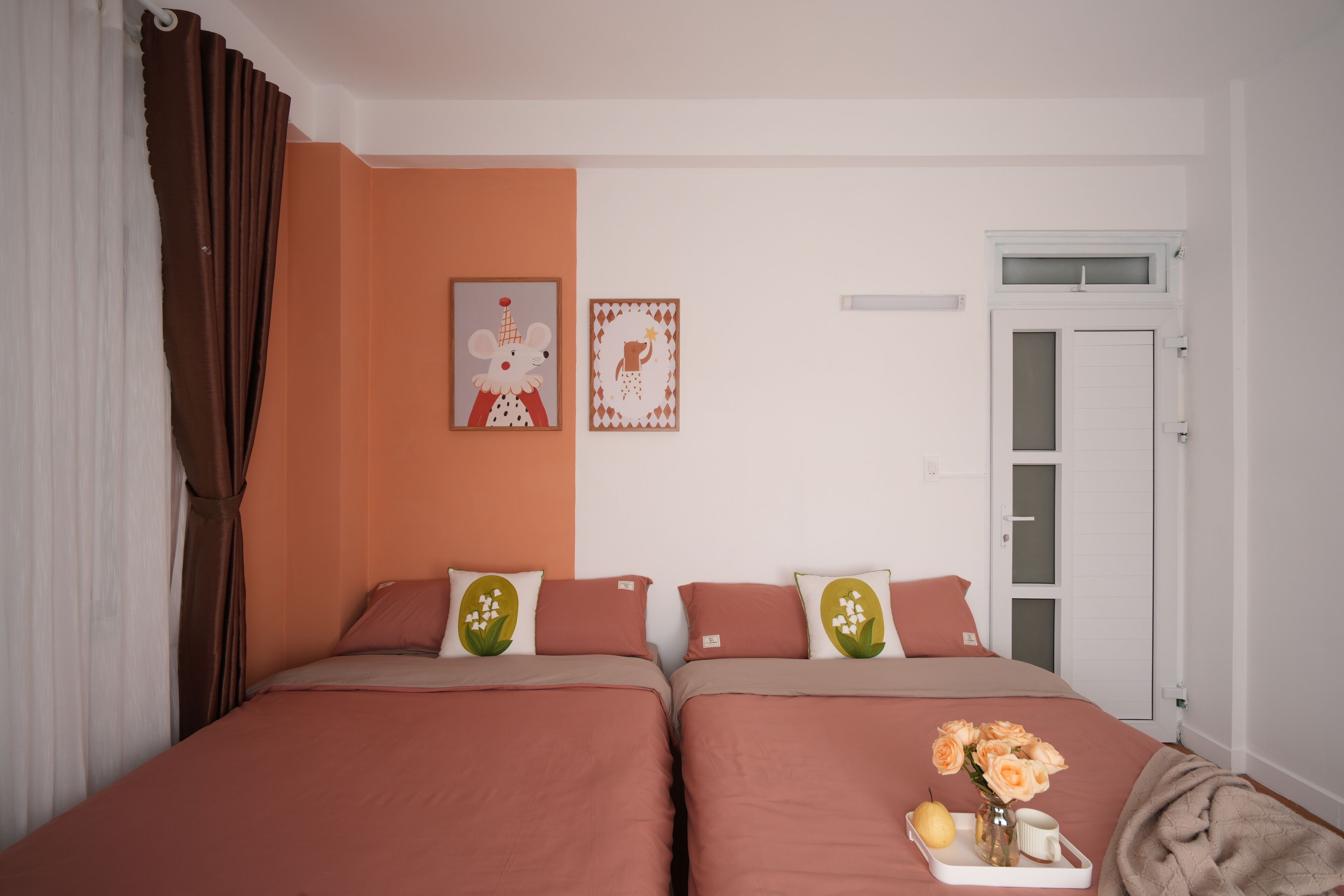 Una cama doble con almohadas a juego, una mesita de noche con un florero y una ventana con persianas.