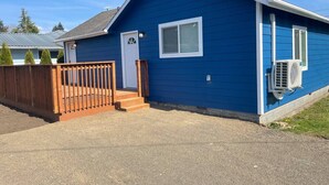 A single-story building with a blue exterior, a wooden fence, and a gravel driveway. - Bogachiel Den – Comfortable Forks Getaway (Forks)