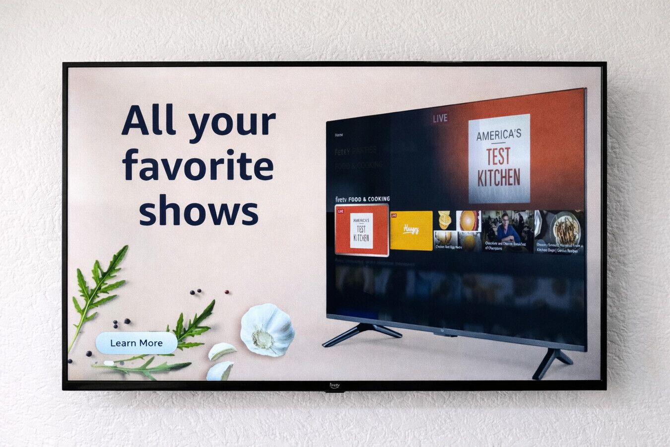 Ein Fernseher zeigt 'AMERICAS TEST KITCHEN' mit einer Schaltfläche 'Mehr erfahren'.