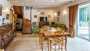 Ein Essbereich mit Holztisch und Stühlen, einem Fernseher und einer Treppe, die in einen anderen Raum führt.