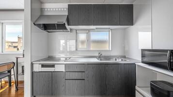 Een koelkast, een magnetron, een kookplaat, kookgerei, borden en bestek