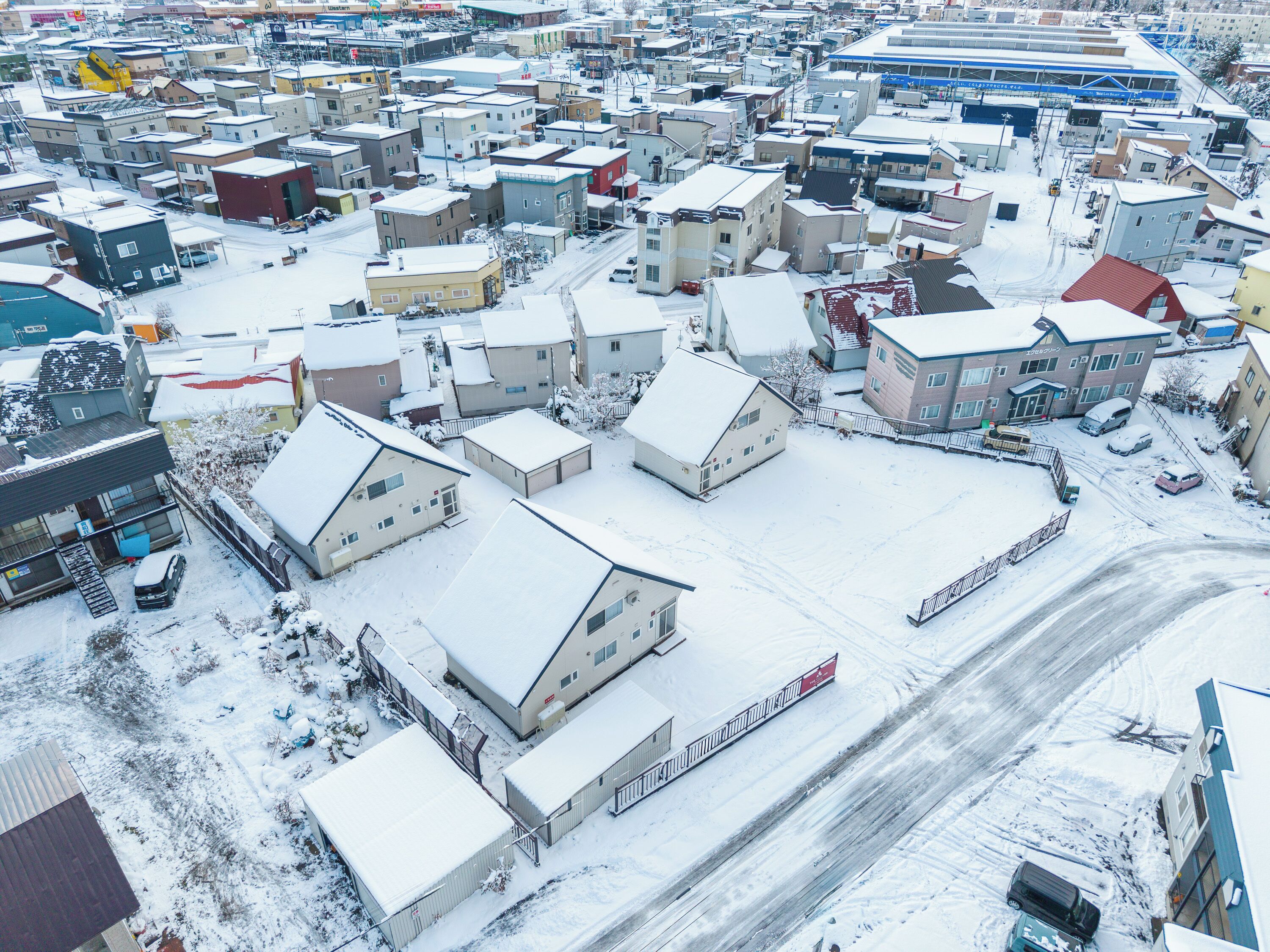 A snow-covered residential area with houses and a train track.