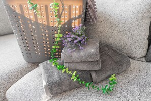 Un sofá gris con textura, una planta pequeña y un cojín gris.