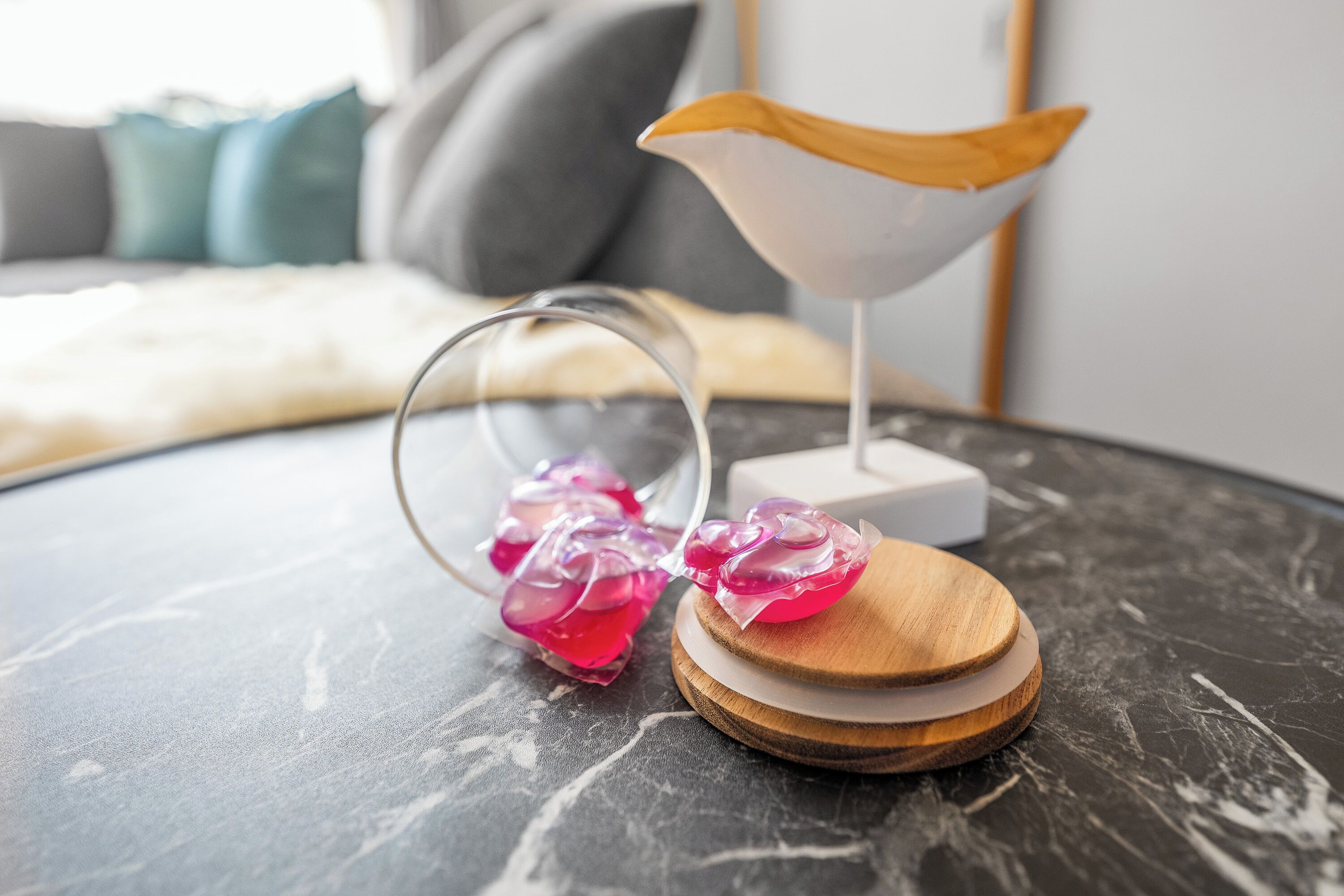 A table with a decorative glass object and a wooden bowl on a marble surface.