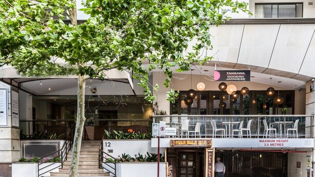 Un restaurant japonais moderne doté d’une terrasse et d’un escalier menant à l’entrée.