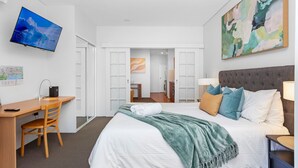 Une chambre d’hôtel moderne, dotée d’un grand lit, d’un bureau et d’une télévision.