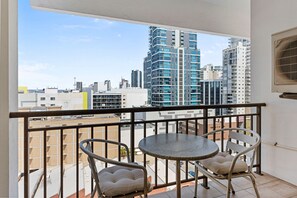 A balcony with a table and two chairs, overlooking a cityscape with high-rise buildings. - Victoria Two - A Sepal Stay (Perth)