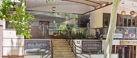 A hotel entrance with a sign reading "ALL SUITES PERTH" and "12 VICTORIA AVENUE".