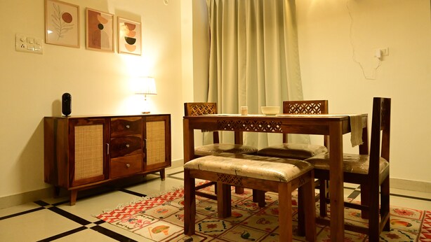 Een eethoek met een houten tafel en stoelen, een kast en een vloerkleed met een patroon.