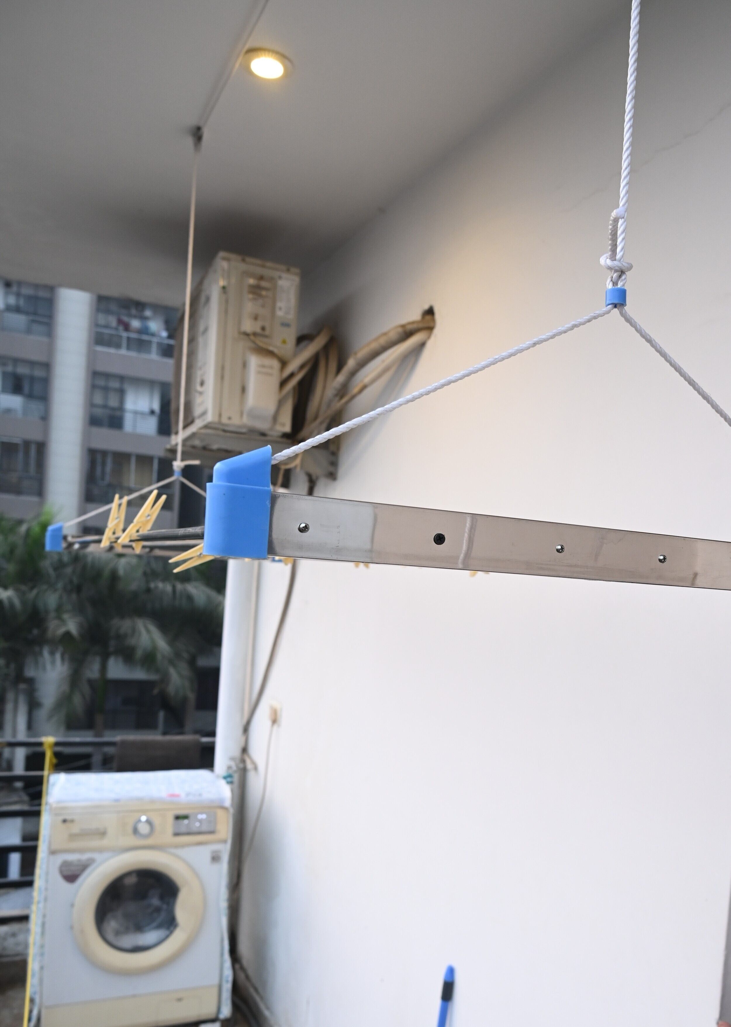 Een wasserij met een wasmachine, een wandgemonteerd katrolsysteem en een gebouw op de achtergrond.