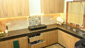 Een kleine keuken met houten kastjes, een inbouwfornuis en een betegelde spatwand.