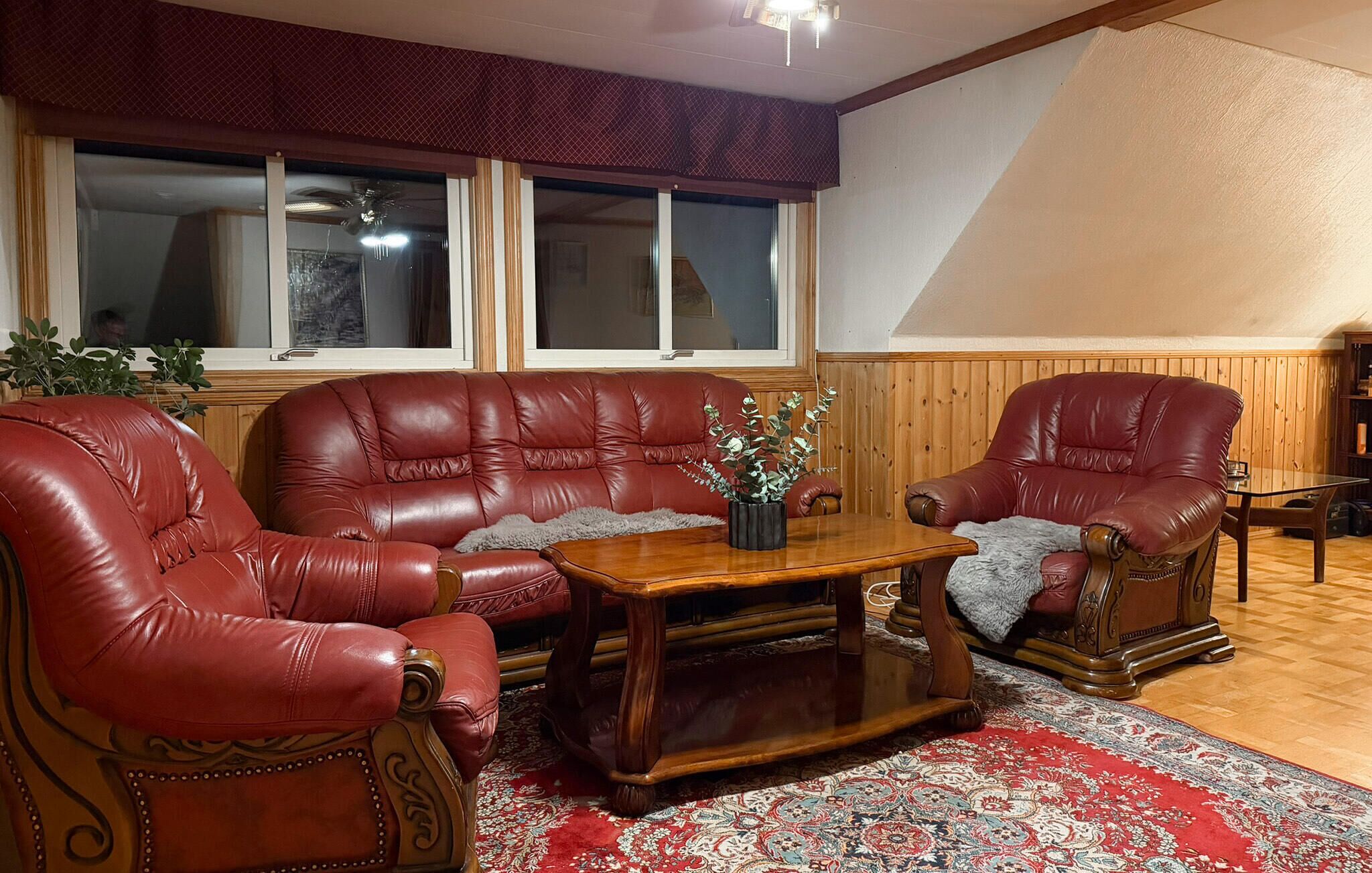 A living room with two red leather armchairs, a wooden coffee table, and a patterned rug.