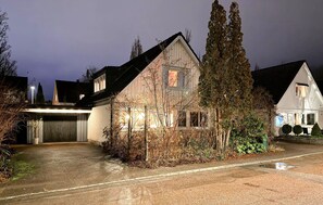 Una casa a due piani con garage, immersa nel verde e con vialetto privato.