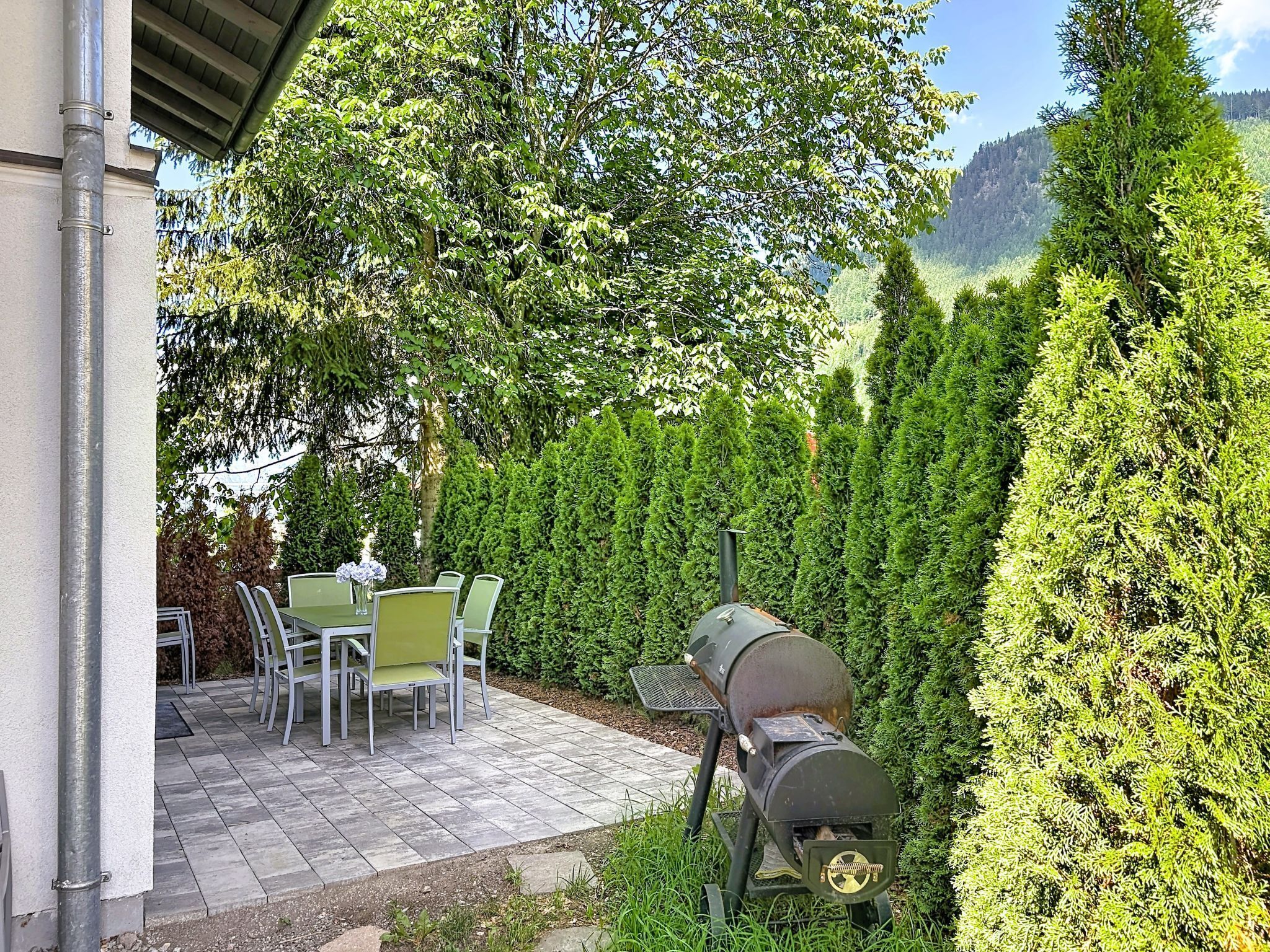 A patio with a grill, chairs, and a table.