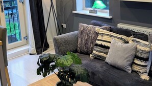 A modern living room with a grey sofa, a wooden coffee table, and a potted plant. - Canal-side haven, short canal walk to city. Pet Friendly and parking! (Leeds)