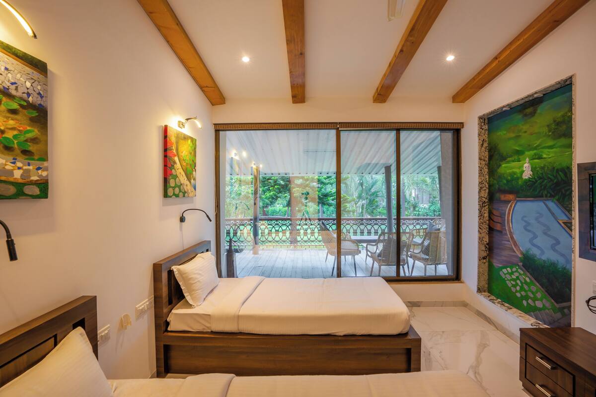 A bedroom with a large window, wooden beams, and artwork on the walls.