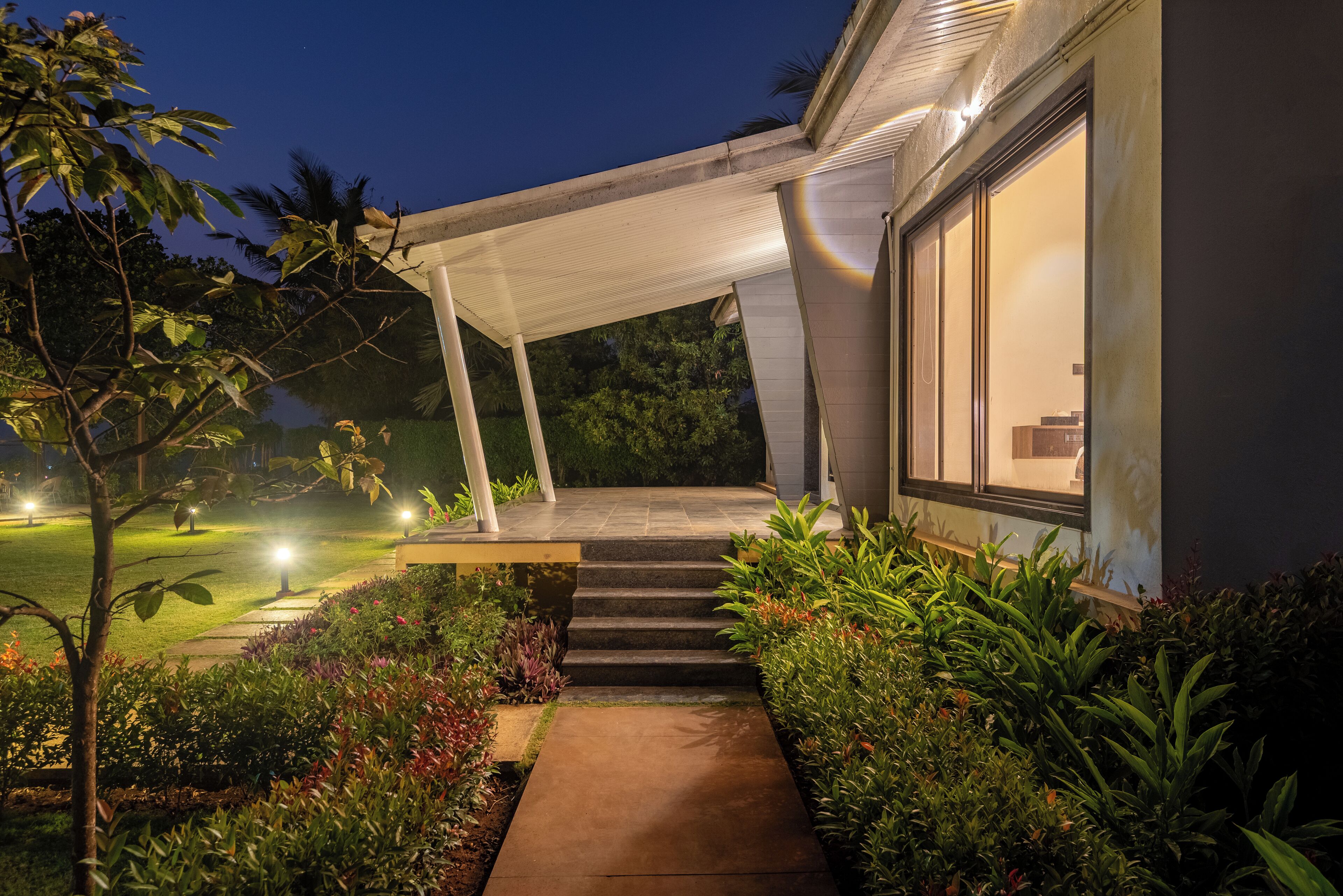 A modern house with a covered porch, a concrete pathway, and well-maintained garden.