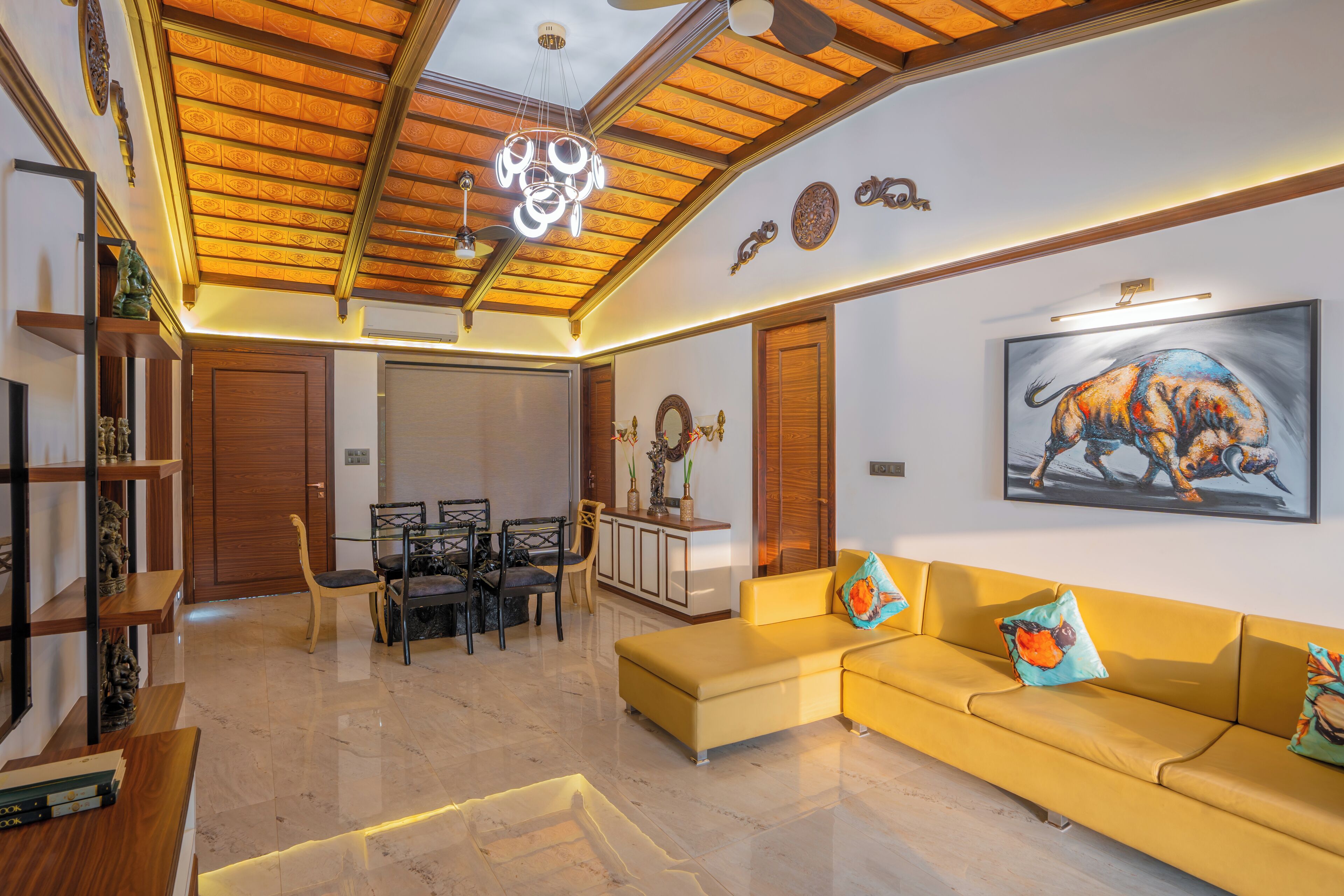 A modern living room with a yellow sofa, a dining area with a wooden table and chairs, and a ceiling with a wooden beam design.