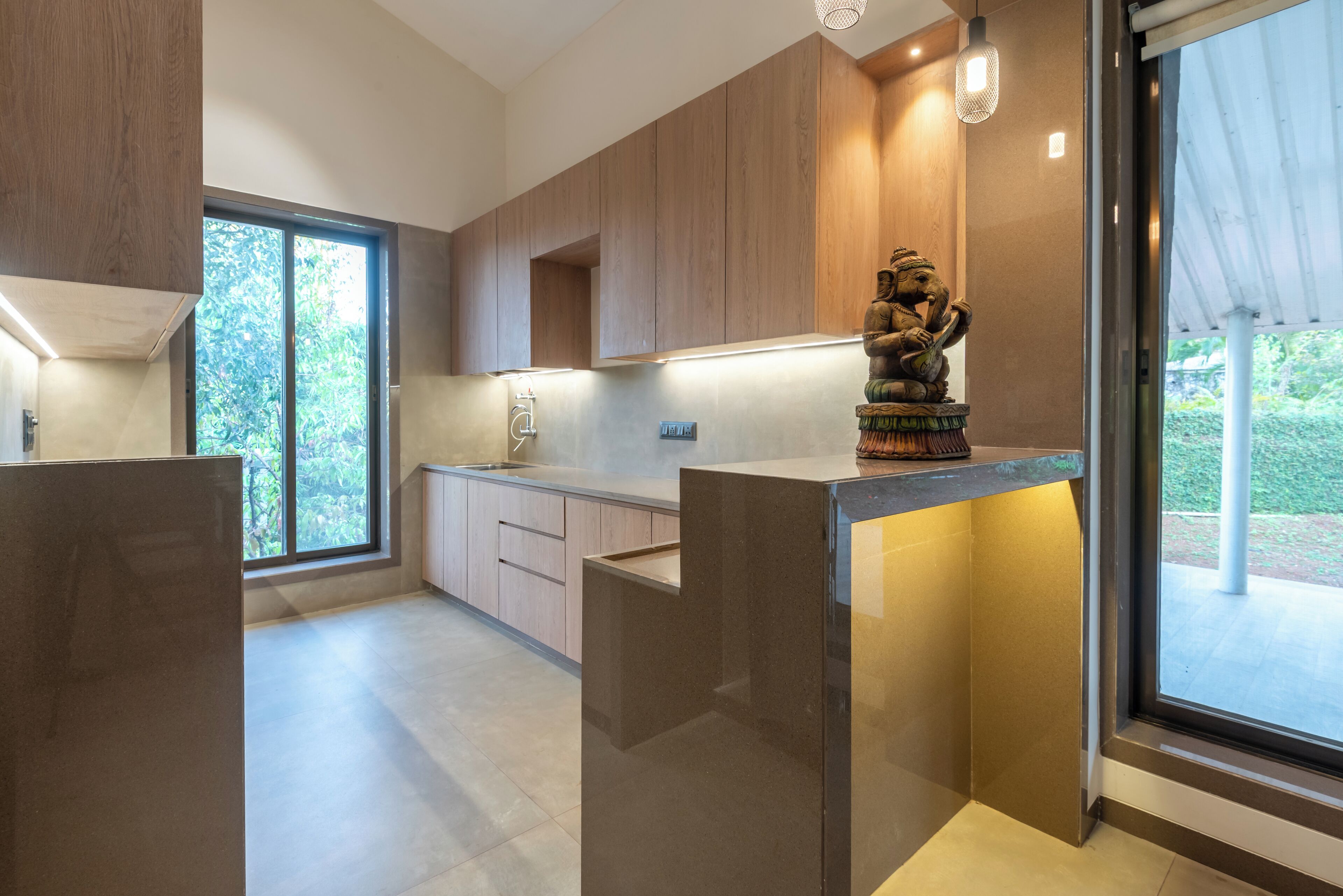 A modern kitchen with wooden cabinets, a marble countertop, and a statue.
