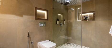 Un baño moderno con ducha envuelta en vidrio, un lavabo blanco y un espejo con iluminación integrada.