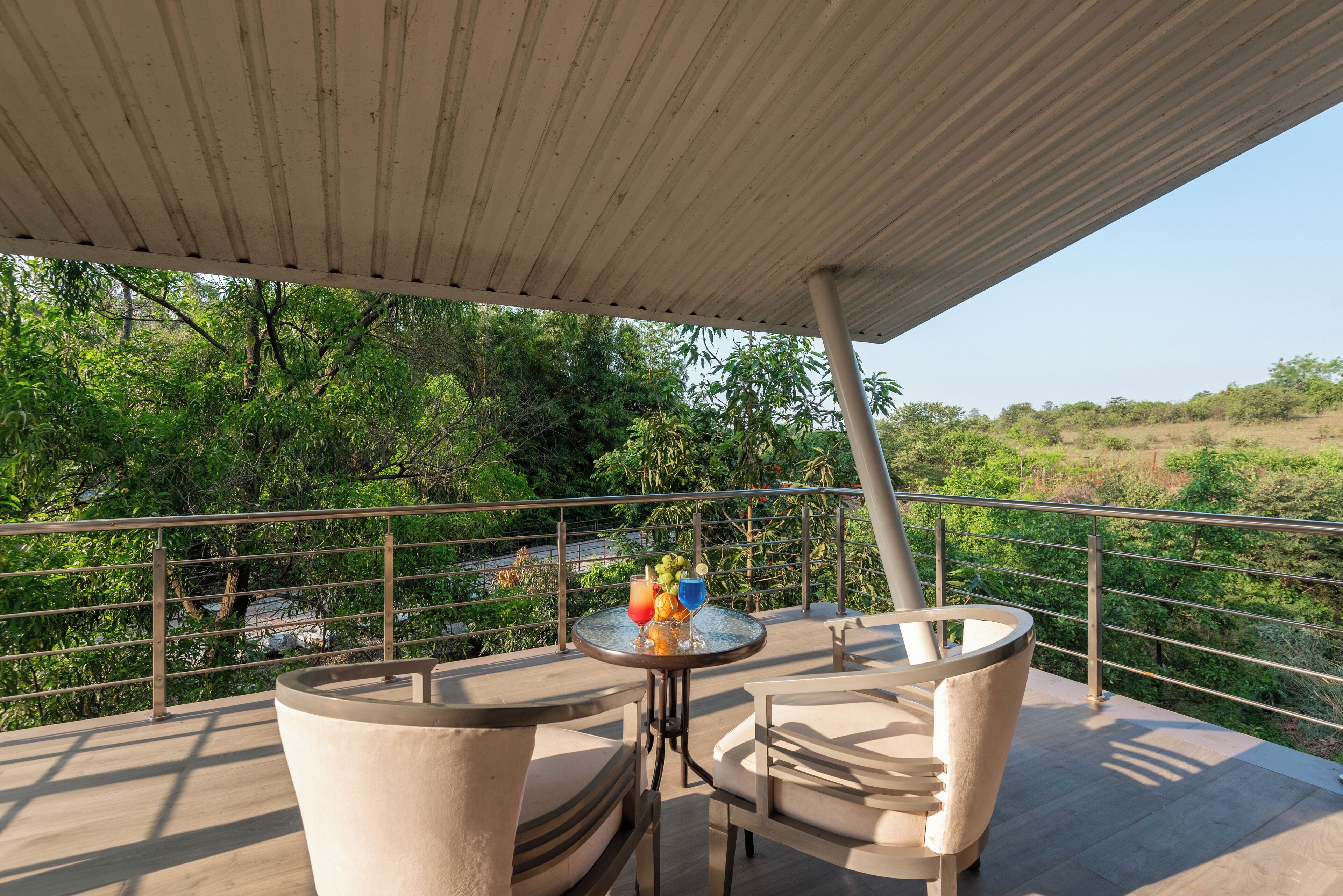 Un balcón con mesa y sillas, con vista a un paisaje verde exuberante.