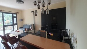 A modern kitchen with a central island, hanging pendant lights, and a view of the outdoors. - 3-Apartment Coastal Italian Villa (San Lorenzo - Civezza)