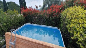A rectangular hot tub with a wooden deck and a ladder, surrounded by lush greenery and flowering bushes. - 3-Apartment Coastal Italian Villa (San Lorenzo - Civezza)