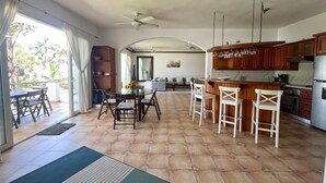 A spacious kitchen with a central island, a dining area with a table and chairs, and a living area with a sofa and a coffee table. - All-inclusive 3bd beachfront central condo with sea views! (Cabarete)