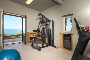 A home gym with a treadmill, weight bench, and exercise ball. - Sea front villa with pool and tennis court - DiCasaInSicilia (Pozzillo)