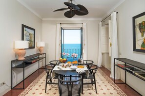 A dining area with a view of the sea, a ceiling fan, and a table set with plates, glasses, and flowers. - Sea front villa with pool and tennis court - DiCasaInSicilia (Pozzillo)
