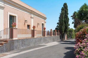 A building with a stone facade, multiple windows, and outdoor lighting fixtures. - Sea front villa with pool and tennis court - DiCasaInSicilia (Pozzillo)