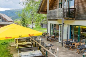 A wooden building with outdoor seating and a yellow umbrella.