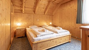 Una habitación de madera con una cama, dos mesitas de noche y una ventana con cortinas.